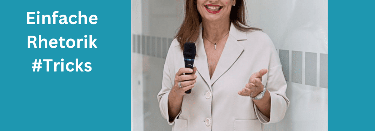 Eine Frau steht da und lächelt in die Kamera, während sie ein Mikrofon hält und eine Handbewegung macht, um ihre Überzeugungskraft zu demonstrieren. Der Text links lautet „Einfache Rhetorik #Tricks“ mit einem Fotonachweis an „Doreilles Hofer“ darunter. Der Hintergrund ist ein heller Innenraum.